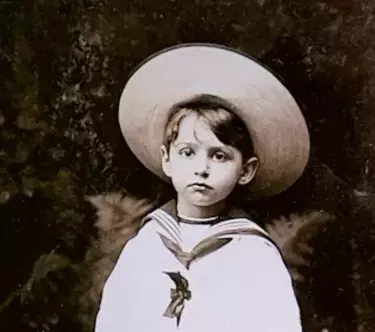 Photo noir & blanc de Jean Hugo enfant, le montrant de face en marinière blanche et avec un chapeau.