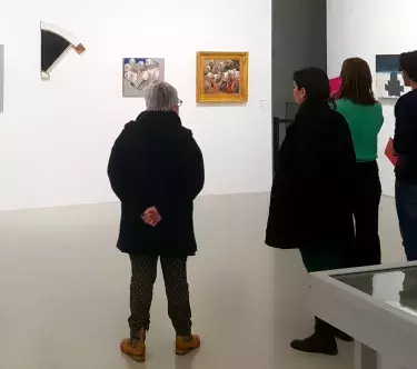 Dans une salle du musée, un groupe de visiteurs, de dos, regarde des œuvres d'art contemporain réalisées par Pierre Buraglio.